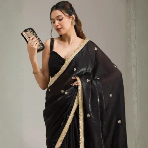 Woman wearing a black georgette saree with gold stonework detailing